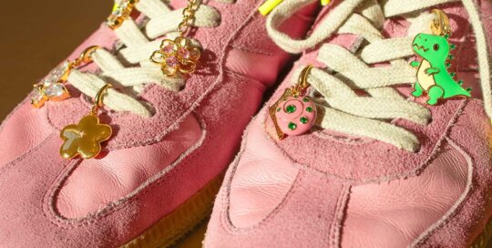 Pink sneakers decorated with stainless steel lace charms in dinosaur, donut, flower, butterfly, and star shapes